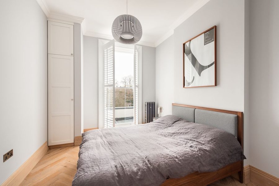 Principal bedroom with upholstered headboard and fitted wardrobe