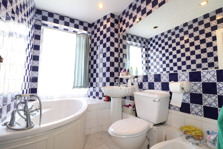 Bathroom with corner bath and patterned tiling